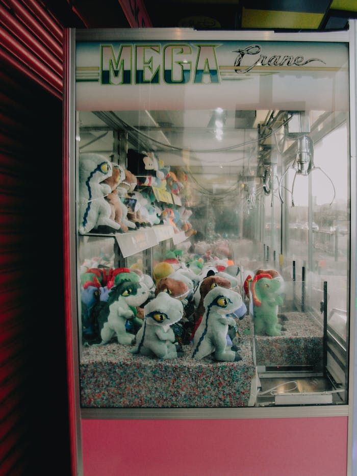 Claw machine with stuffed dinosaur toys inside an amusement arcade.