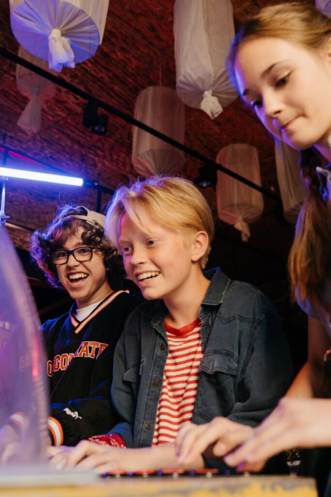 Group of teenagers having fun playing arcade games indoors with cheerful expressions.